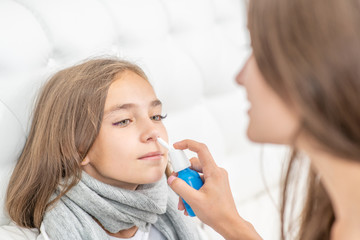 Mother using nose spray to cure her teen girl at home