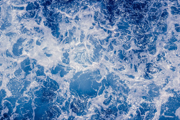 Pale blue sea surface with waves and foam, abstract background