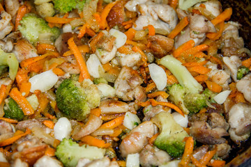 meat broccoli carrots onions garlic with sesame seeds all together in a pan. looks like a background