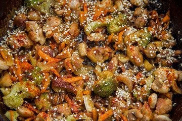 meat broccoli carrots onions garlic with sesame seeds all together in a pan. looks like a background