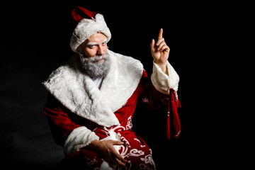Obraz premium Portrait of a bad brutal mature Santa Claus showing middle finger signs, isolated on black background