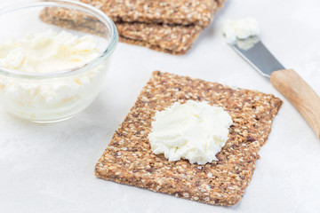 Thin multi seed  crispbread with cream cheese, preparing bruschetta with cheese and salmon, horizontal