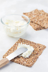 Thin multi seed  crispbread with cream cheese, preparing bruschetta with cheese and salmon, vertical