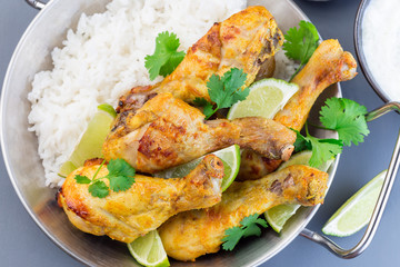 Indian chicken tandoori, marinated in greek yogurt  and spices, served with lime wedges, cilantro and basmati rice, horizontal, top view