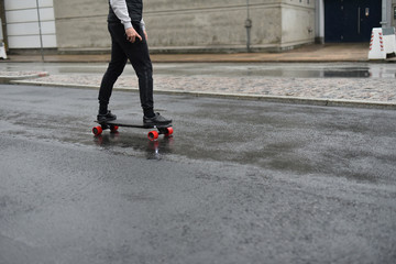 Obraz na płótnie Canvas man rides on electric skateboard by rainy street