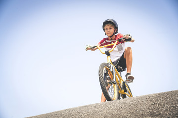 Young cyclist with bmx ready to start. Trendy young boy wearing helmet riding a bicycle looking the...