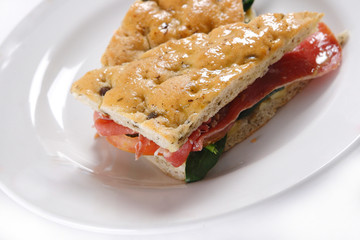 Traditional bread sandwich with serrano ham, cheese and spinach leaves.