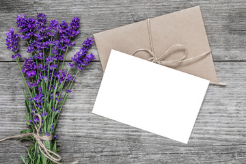 blank white greeting card with lavender flowers and envelope on rustic wooden table. flat lay. top view. mock up