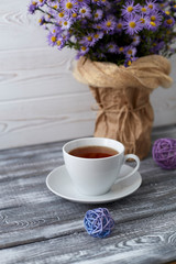 Romantic background with a cup of tea, lilac flowers in a vase on a gray wooden table