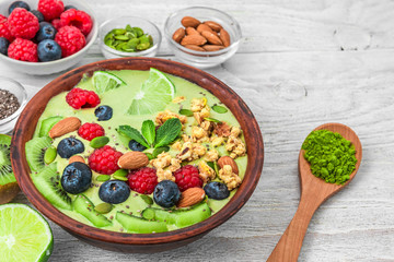 matcha green tea smoothie bowl with fresh fruits, berries, nuts, seeds and granola for healthy vegetarian diet breakfast