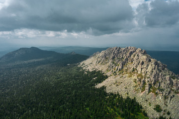 aerial view of ural nature. drone flying over the steep stony slope with coniferous and deciduous mixed forest at the foot of mountain. natiounal park, ecological protected area in Russia