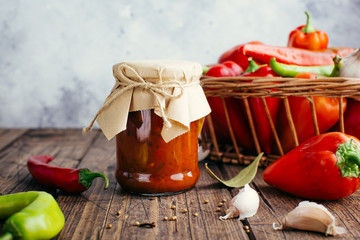 Adjika in a jar on a wooden background, spicy tomato sauce