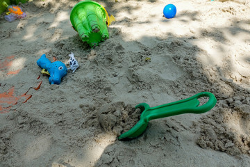A sandbox with children's toys scattered in a mess.