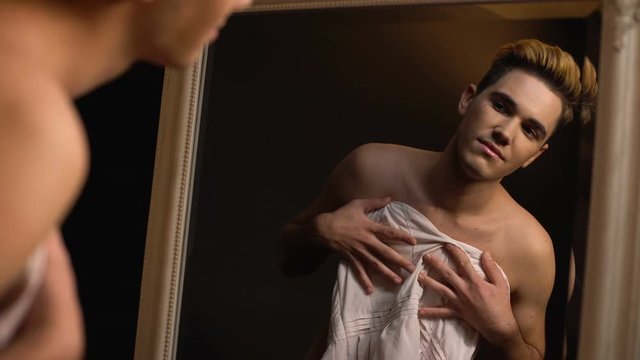Transgender holding dress looking in mirror, feeling like woman, self-identity