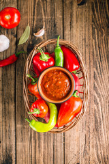 Adjika, spicy tomato sauce, vegetable snack on a wooden background