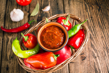 Adjika, spicy tomato sauce, vegetable snack on a wooden background