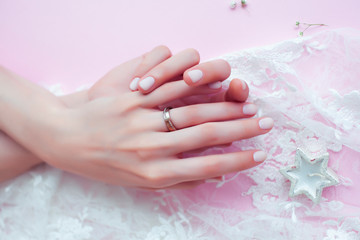 Fototapeta premium woman hands with manicure and wedding ring among white lace