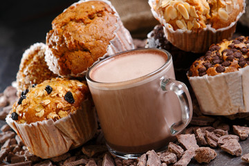 Cup of hot chocolate with chocolate beans, cookies, cupcakes and cinnamon.