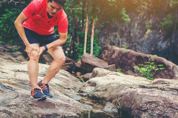 Man runner injury in knee pain while running trail in the forest