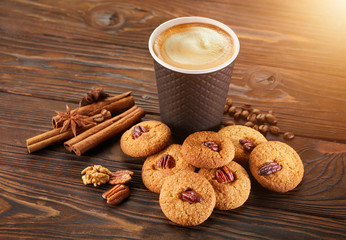 Paper cup of coffee with biscuit cookies on wooden table