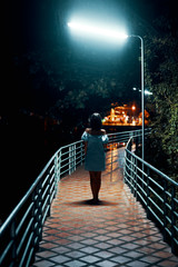 Young lonely woman walking on the bridge at night