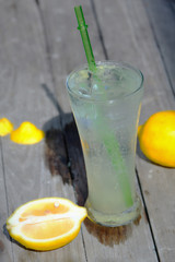 Fresh cocktail with soda, lemon on a wooden background.