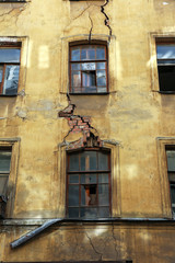 old house - wall of an empty and abandoned city house with deep cracks and broken windows