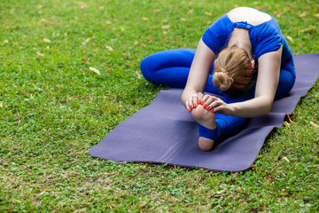 Fototapeta na wymiar White girl in a city park in the morning doing yoga, copy space, text