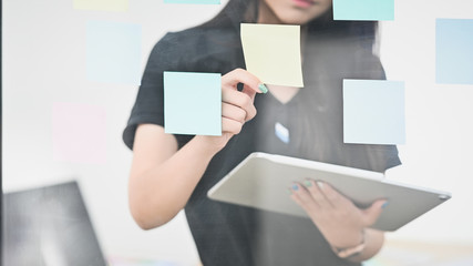 Obraz premium Woman holding sticky note and holding digital tablet on windows glass.
