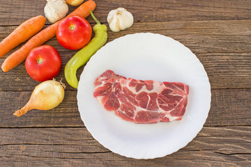 Raw pork meat chop with vegetable on wooden table