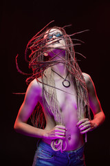 A beautiful young slim girl with creative make-up and a hairstyle of cornrows, covers her breast...