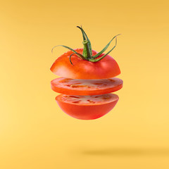 Fresh ripe red tomatoes flying in the air isolated on yellow background.