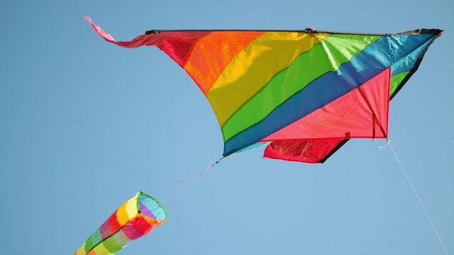 A colorful kite flying in the blue clean sky on sunny day. LGBT flag symbol. Freedom and summer holiday concept.