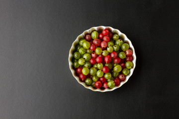 Gooseberries in a metal baking pan on a black background