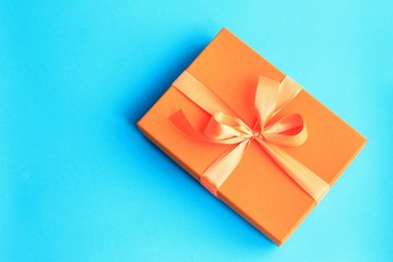 Craft paper gift with orange ribbon on dark blue background with copy space.