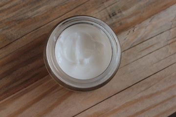 A jar with cosmetic cream stands on a wooden background.