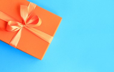 Craft paper gift with orange ribbon on dark blue background with copy space.