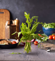 Fresh raw green arugula falling in the air  on kitchen table over dark concreate background