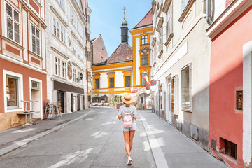 Fototapeta na wymiar young asian woman with backpack and hat walking on city street in Europe