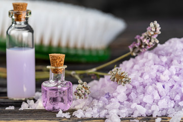 Obraz na płótnie Canvas Lavender spa setting: salt, essential oil and dried flowers natural spa products and decor for bath on dark background.