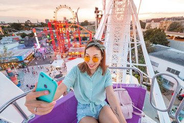 Happy asian woman smiling and taking selfie photo on a ferris wheel