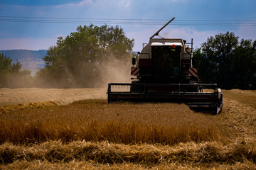 combine harvester working in dusty field
