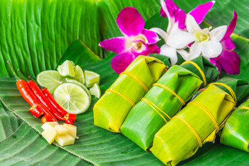 traditional thai food style sour porks wrapped with banana leaf decorated with ingredient orchid flower