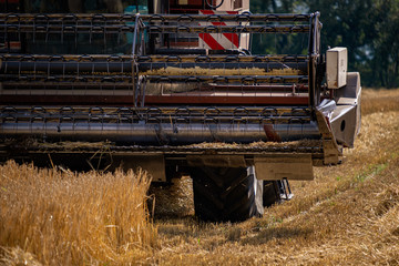 Closeup of front right half of combine harvester in field