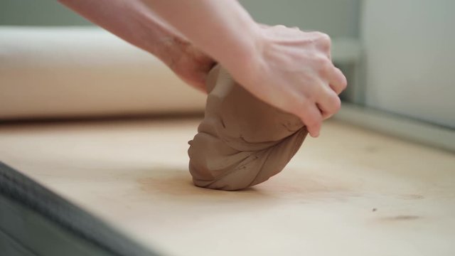The hands of the master crumple a piece of clay