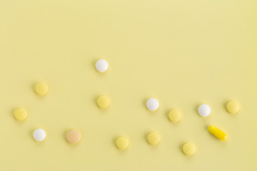 various round tablets and capsules with antibiotics on a yellow background