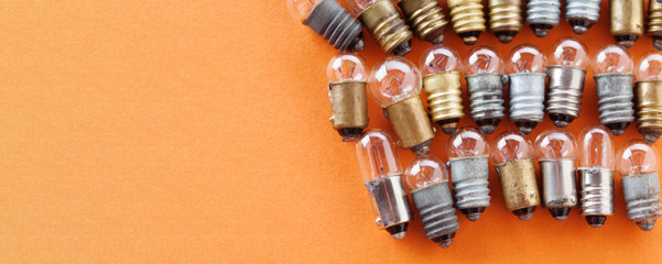 Light bulbs with textured gold bronze and silver surface. Vintage lamps collection macro view. Orange background, shallow depth of field photo. copy space