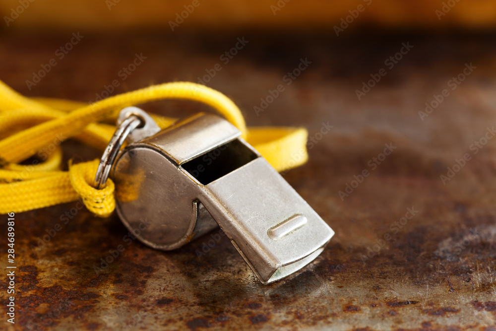 Wall mural Vintage silver whistle on rusty metallic background. Referee trainer sport competition tool instrument, start finish stopping game and attention moments equipment. Close-up photo.