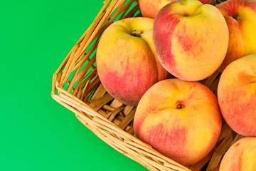Peach fruit in basket on green background