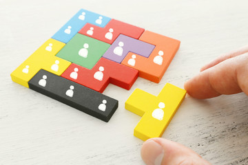 business concept image of tangram puzzle blocks with people icons over wooden table ,human resources and management concept